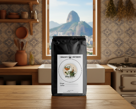 A black coffee bag with a white label stands on a wooden table in a rustic kitchen with arched window showing a mountain landscape.